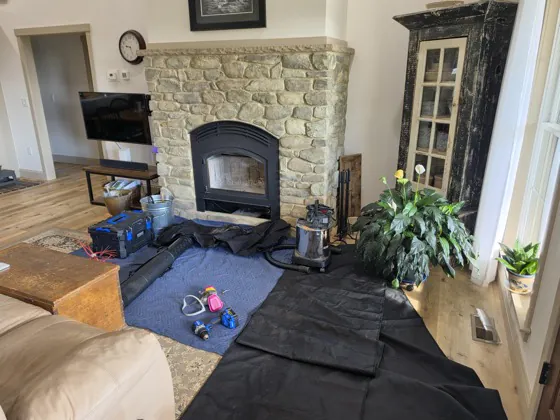 Sweep rods, vacuum, and drop cloths set up in front of a stone fireplace